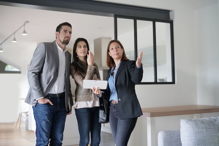 Agent immobilier faisant visiter une maison moderne à un couple