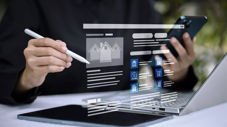 Professionnel consultant son smartphone devant son ordinateur portable. Un écran affiche plusieurs KPI relatifs à l'immobilier