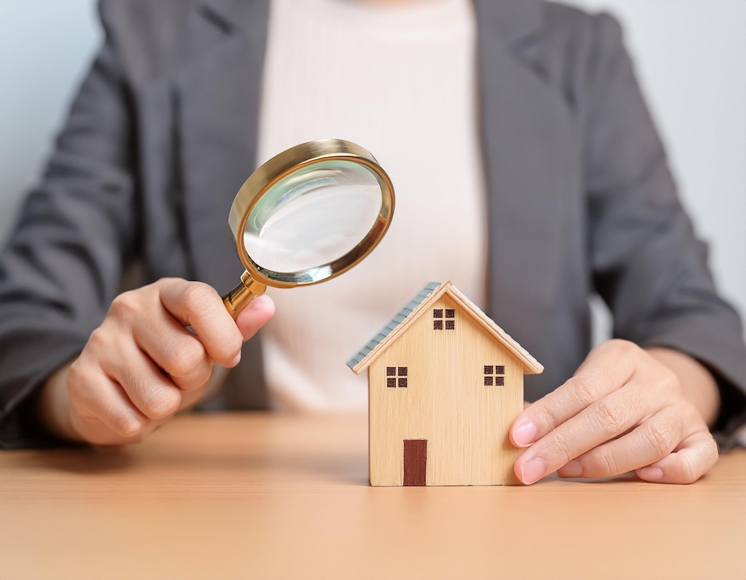 Homme observant une maquette de maison à la loupe