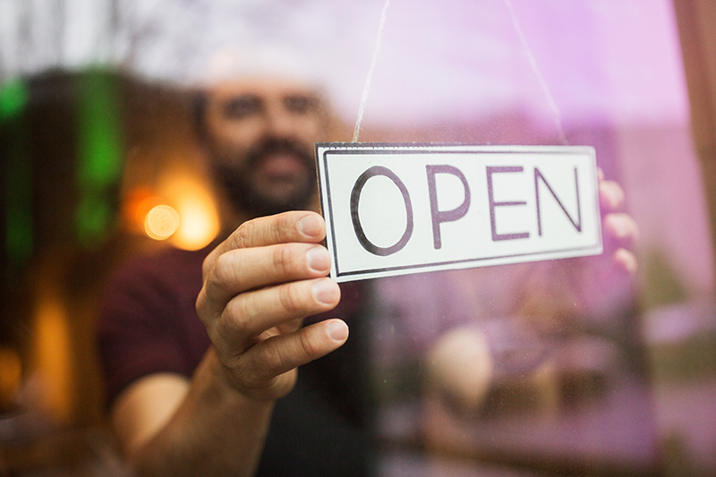Homme qui tient une pancarte open en vitrine Ubiflow